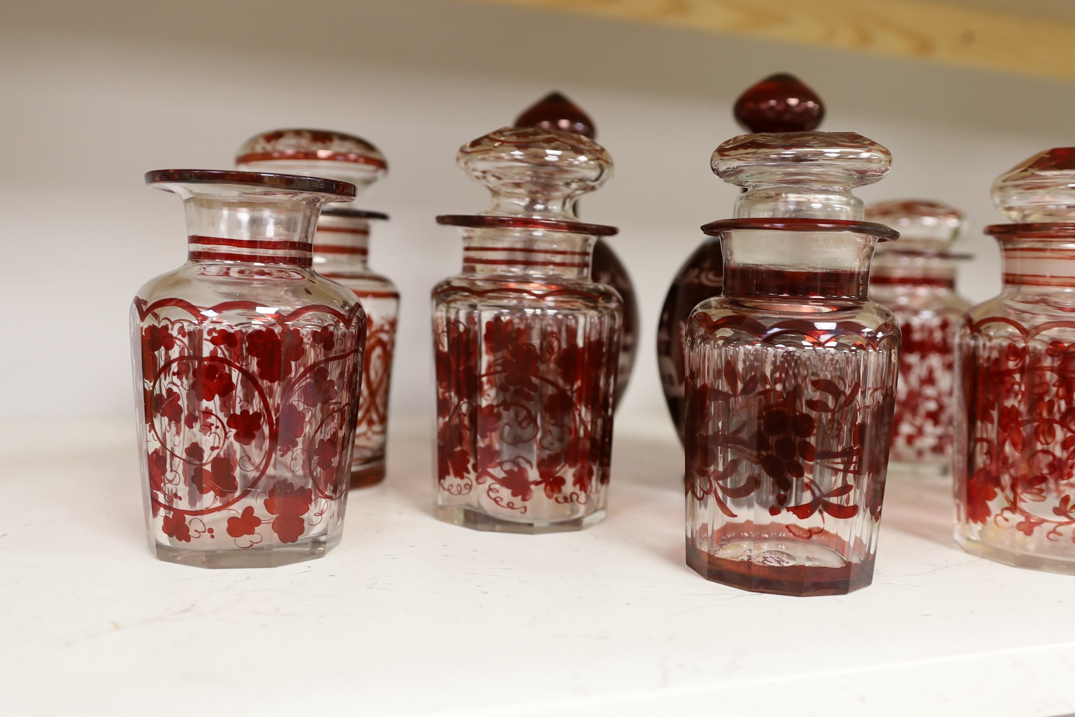 A pair of 19th century wheel engraved ruby glass decanters with stoppers, and seven ruby stained glass jars, tallest 21cm (9)